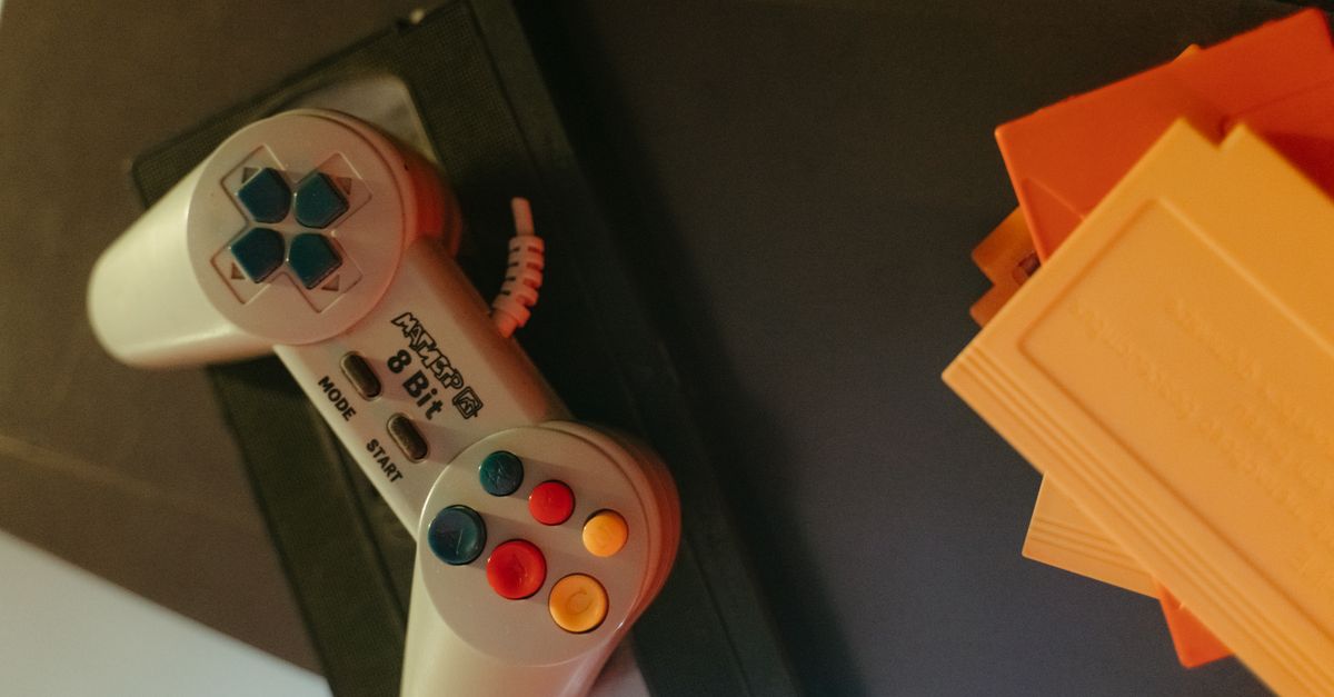 A vintage 8-bit game controller with colorful buttons next to classic game cartridges.