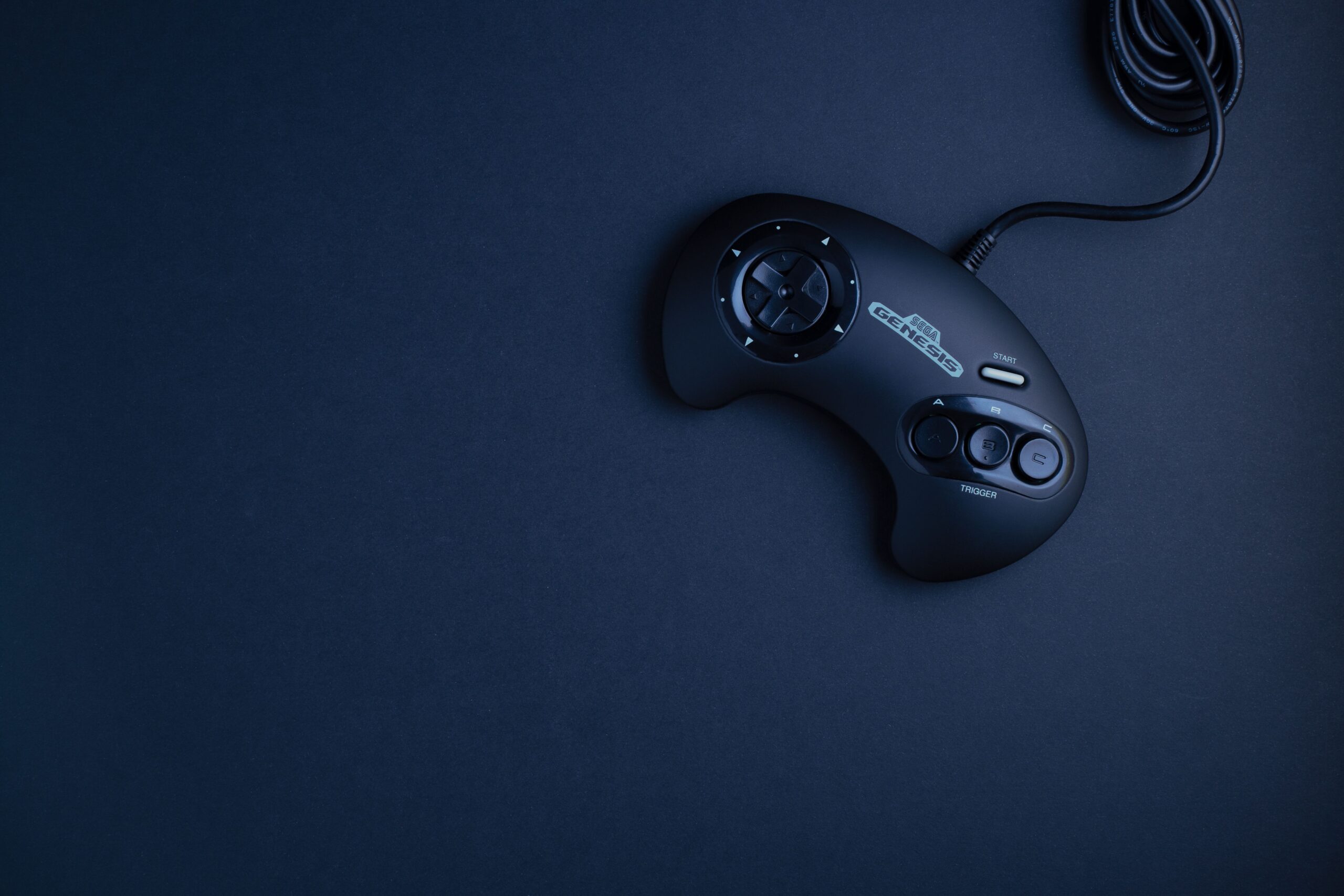 Navy blue vintage game console controller photographed from above on a dark background