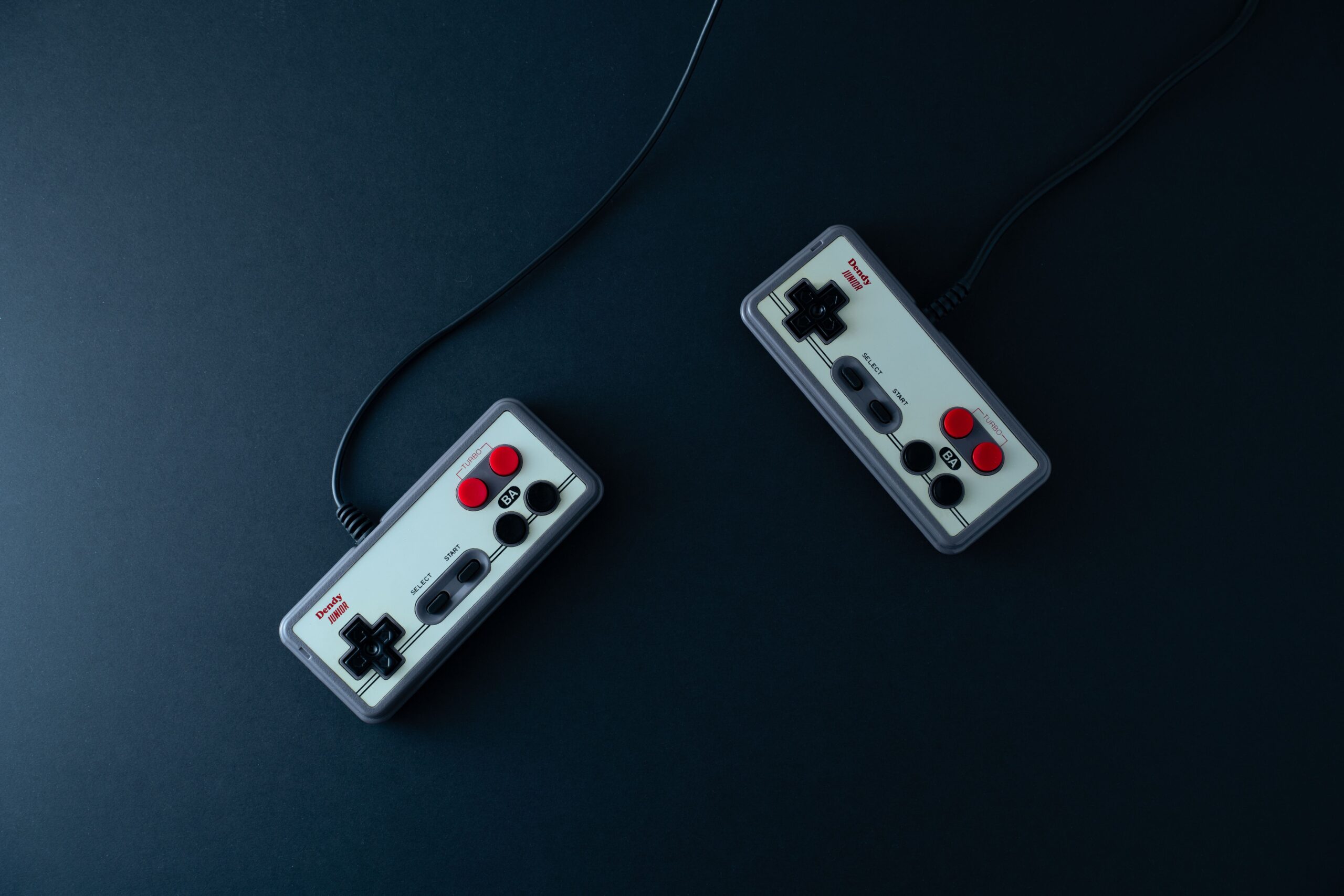 Two retro gaming controllers on a dark background, vintage console gaming