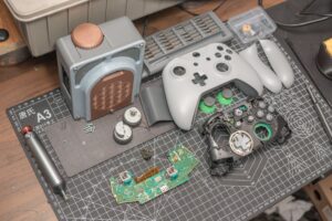 Controller di una console retro smontato con componenti elettronici su un tappetino da lavoro per riparazione e modding