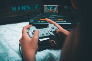 Hands holding a retro console controller with a Sega Mega Drive in the background, the perfect image for a guide to retro consoles with built-in games.