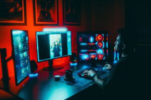 Game developer al lavoro su postazione multi-schermo per sviluppare videogiochi