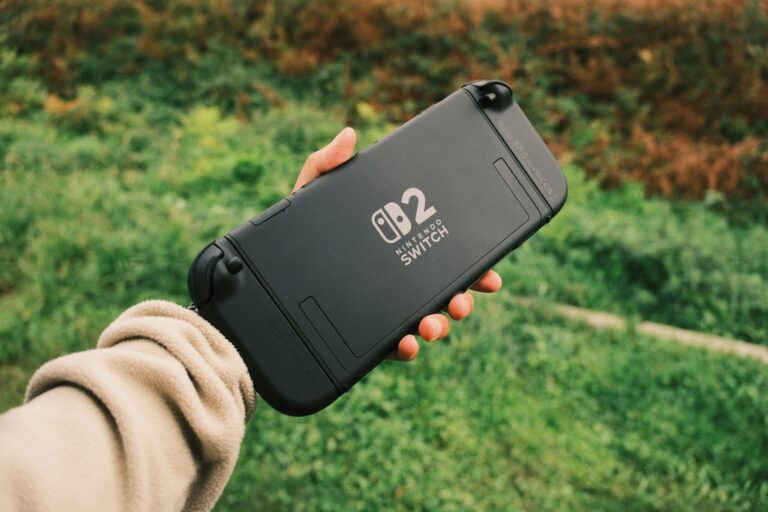 Hand holding a Nintendo Switch console outdoors, perfect for retro gaming on the go