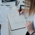 Game designer che pianifica il progetto e scrive il game design document sul tavolo di lavoro