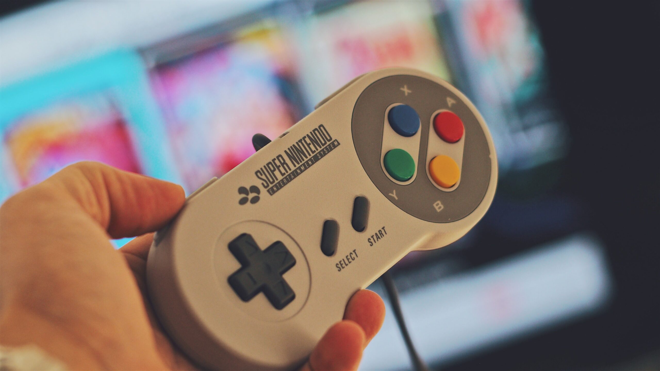 Hand holding a classic Super Nintendo controller while playing retro games online in a browser.
