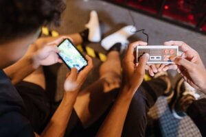 Teenagers playing mobile and retro video games indoors with a controller