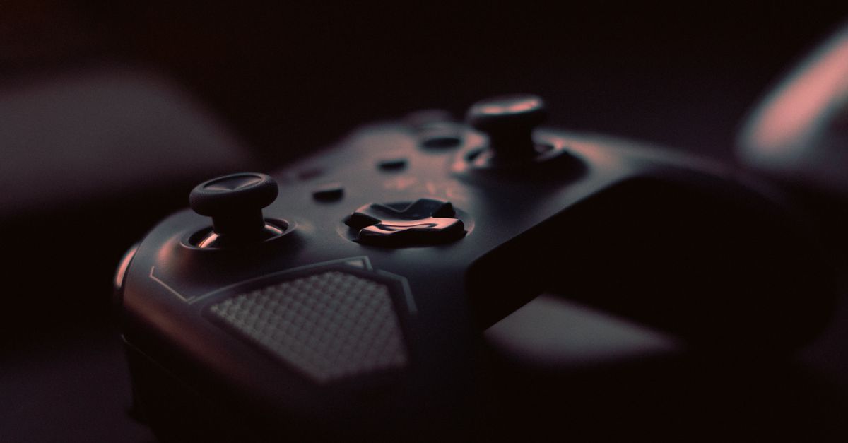 A close-up shot of a game controller in low light, highlighting its design and buttons.