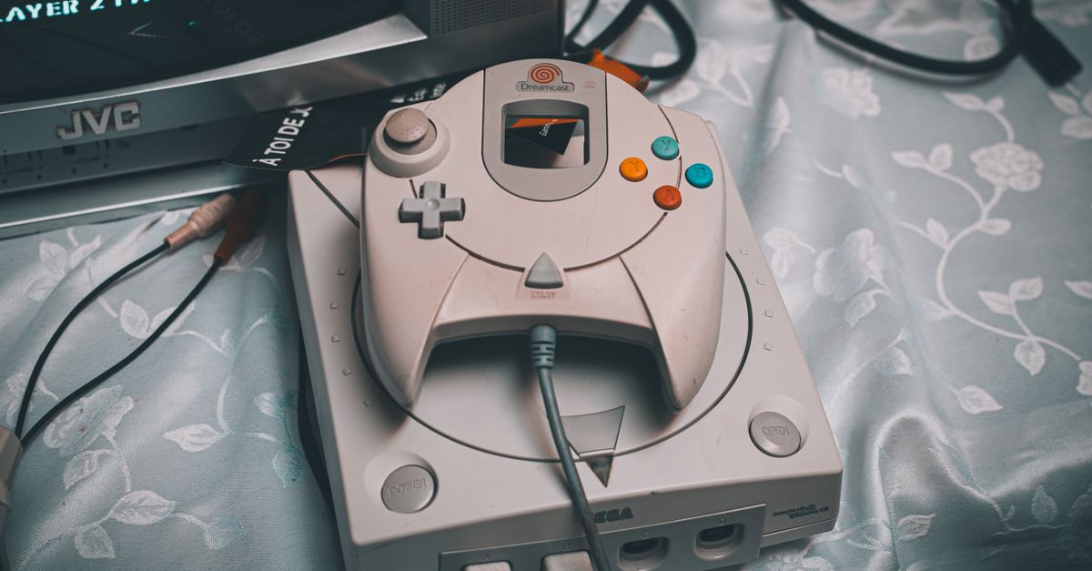 Close-up of a Sega Dreamcast console with controller and CRT monitor in a retro gaming setup.